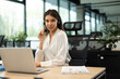 © ty - Cheerful female manager sitting at office desk and performing corporate tasks using wireless connection on digital gadgets