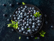 Blueberries in a black plate on a dark background.