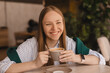 © zvkate - Close-up of laughing blonde girl wear shirt with coffee in coffee shop. Lovable lady sitting in restaurant and holding cup of coffee, laughing, have good mood, joking.