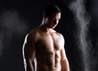 © peopleimages.com - Body, fitness and man with abs in studio with chalk, exercise and healthy from training on black background. Bodybuilder, sports or dark for male athlete model, muscular or dust with confident person