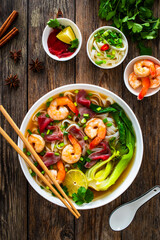 Poster - Shrimp and beef Pho soup - Vietnamese soup with shrimps and raw beef slices on wooden table
