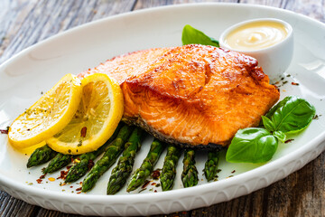 Sticker - Fried salmon steak with cooked green asparagus and mayonnaise served on wooden table
