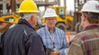 © khonkangrua - Three senior engineers in discussion at a busy construction site with heavy machinery.