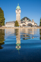 Wall Mural - View of the train station in Limoges reflecting in blue water, vertical photography, France