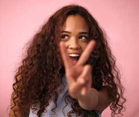 Poster - Girl, happy and peace sign with hair in studio on pink background for treatment, growth or care. Female person, gen z and isolated with trendy or natural hairstyle, curls and soft for fresh texture