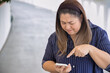 Angry Unhappy Frustrated Middle aged Asian aunt, aged woman using smartphone, negative expression, concept image for slow connection, internet scam, internet fraud, poor cyber security