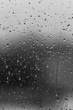 Fototapeta Zachód słońca - Rain drops on window glass closeup macro. Black and white abstract background texture 