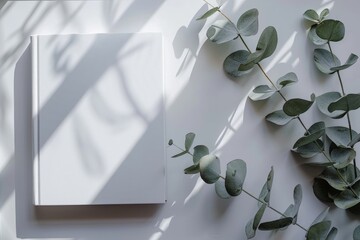 Sticker - A white book sits on a table next to a bunch of green leaves