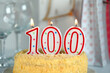 Celebration cake with burning candle number 100