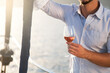 Man drinking wine on yacht at sea and traveling. Summer vacation at sunset. Happy tourist relaxing, enjoying holidays with wineglass of beverages. Lifestyle moments, life satisfaction and pleasure