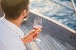 Man drinking wine on yacht at sea. Travel lifestyle in summer vacation, picnic at sunset. Happy tourist relaxing and enjoying holidays with wineglass of alcohol beverage. Life satisfaction. Close up