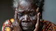 An Indigenous elder woman grimaces and massages her scalp, conveying feelings of stress or annoyance.