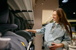 Happy pregnant woman choosing comfortable and safety car seat for newborn