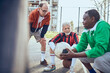 © Davor - Senior soccer team taking a break and strategizing during game on urban court