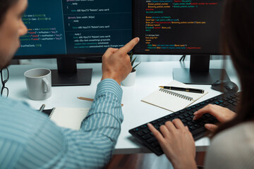 Team skilled developers program coding discussing creative website planning software project on two screen monitor's full stack data analyzing design at office with back side view concept. Postulate.
