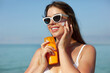 Woman smile applying sun cream on face. Skincare. Body Sun protection. sunscreen. Female in hat smear moisturizing lotion on skin