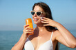 Beautiful woman applying cream sunscreen on tanned face. Sunscreen. Skin and body care. The girl uses a sunscreen for her skin. Portrait of a female holding suntan lotion and moisturizing sunscreen.