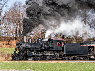 Canvas Print - A steam train is traveling down the tracks, leaving a trail of smoke behind it