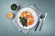 Traditional American pancakes with spinach, pine-nuts and raisins served as top view on a Nordic design plate with cutlery