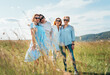 © Soloviova Liudmyla - Portrait of four cheerful smiling women holding hand in hand walking by a high green grass meadow. They looking at the camera. Woman's friendship, relations, and happiness concept image.