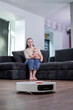 Robotic vacuum cleaner cleaning the living room while mother and son playing