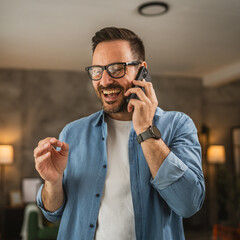 Wall Mural - Portrait of adult man stand while talk on mobile phone and hold cup