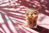 Minimalistic studio shot featuring sunlit cold summer iced coffee with milk in tall glass with golden straw on pink background. Cafe menu concept.