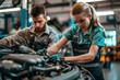 Female and male mechanic work on a car engine in a garage