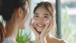beauty skin care asian woman with brunette ponytail both hands touches her face smiling