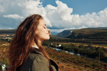 a woman standing on a hill overlooking a valley, looking up at the sky in awe of nature's beauty