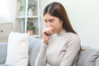 © KMPZZZ - Unhealthy sickness asian young woman, girl unwell with coughing, have cold, sore throat on sofa, couch at home, suffering with symptom cough feeling bad. Health care of Coronavirus, covid-19 concept.