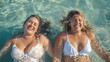 © Antto-AI - A couple of beautiful plus size women with swimwear bonding and having fun at the beach - a pair of curvy female friends enjoying summertime at the sea, concepts about body acceptance, body positive