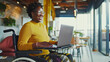 Joyful woman in wheelchair working on a laptop in a bright coworking space.
