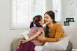 Young girl gives a bouquet of white flowers to mother in cozy living room. Happy mother's day concept
