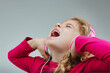 Blonde curls, pink shirt, singing with headphones