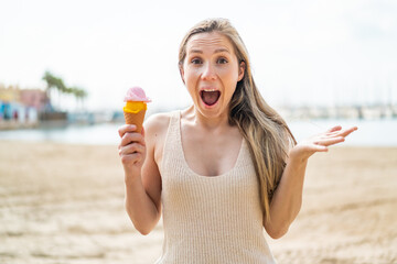 Wall Mural - Young blonde woman with a cornet ice cream at outdoors with shocked facial expression