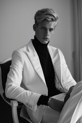 Wall Mural - B&W minimalist elegance with a blonde caucasian male model. Man poses in a sleek and modern setting, dressed in monochrome separates, clean lines, embodying timeless sophistication and simplicity