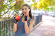 Young pretty sport woman with an apple at outdoors shouting with mouth wide open