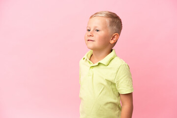 Wall Mural - Little Russian boy isolated on pink background looking up while smiling