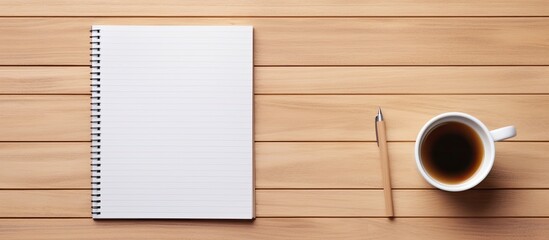 Fototapete - Top view of a wooden office desk table with a blank notebook page a pen and a cup of coffee The image has copy space and is captured in a flat lay style