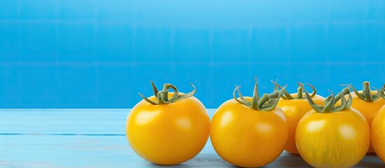 Wall Mural - Close up of ripe yellow tomatoes on a light blue wooden table with copy space image available for text
