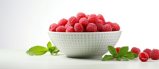 Aufkleber - A closeup copy space image of a bowl containing fresh raspberries and mint leaves placed on a light background