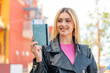 Young pretty blonde woman holding a passport at outdoors with happy expression