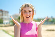 Young pretty blonde woman at outdoors surprised and listening music