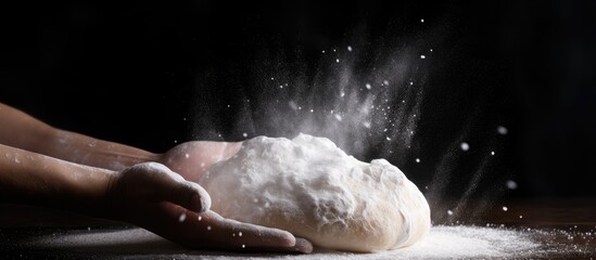 Aufkleber - A pizza dough is being tossed in the air scattering flour in a freeze motion resembling a cloud of flour suspended in black surroundings The dough is kneaded by a cook s hands Copy space image