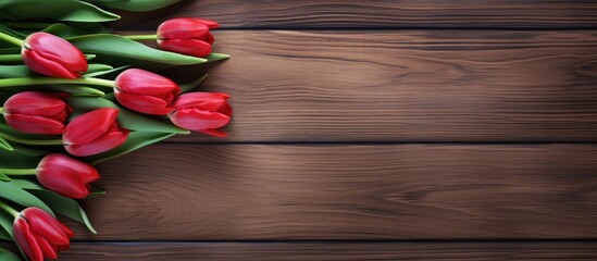 Wall Mural - A top down view of red tulips displayed on a rustic wooden table with ample empty space for other elements in the image