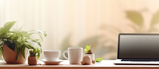 Poster - During the quarantine teleworking has become common with people setting up their workstations in bright kitchens A laptop is placed on a table alongside a flowerpot phone and cup leaving copy space f