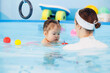Swimming training for baby girl with trainer in pool. Sport activity for health children concept