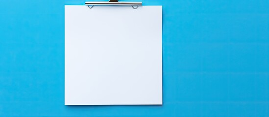Poster - isolated on a blue background there is a white paper note held in place by a paper clip the image of