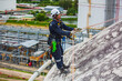 © chitsanupong - Male worker down height tank roof rope access safety inspection thickness weld of storage tank.